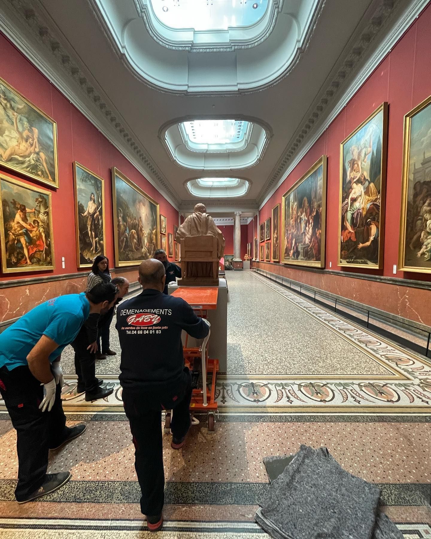 Focus sur un déménageur qui pousse un chariot avec une statue dans un musée