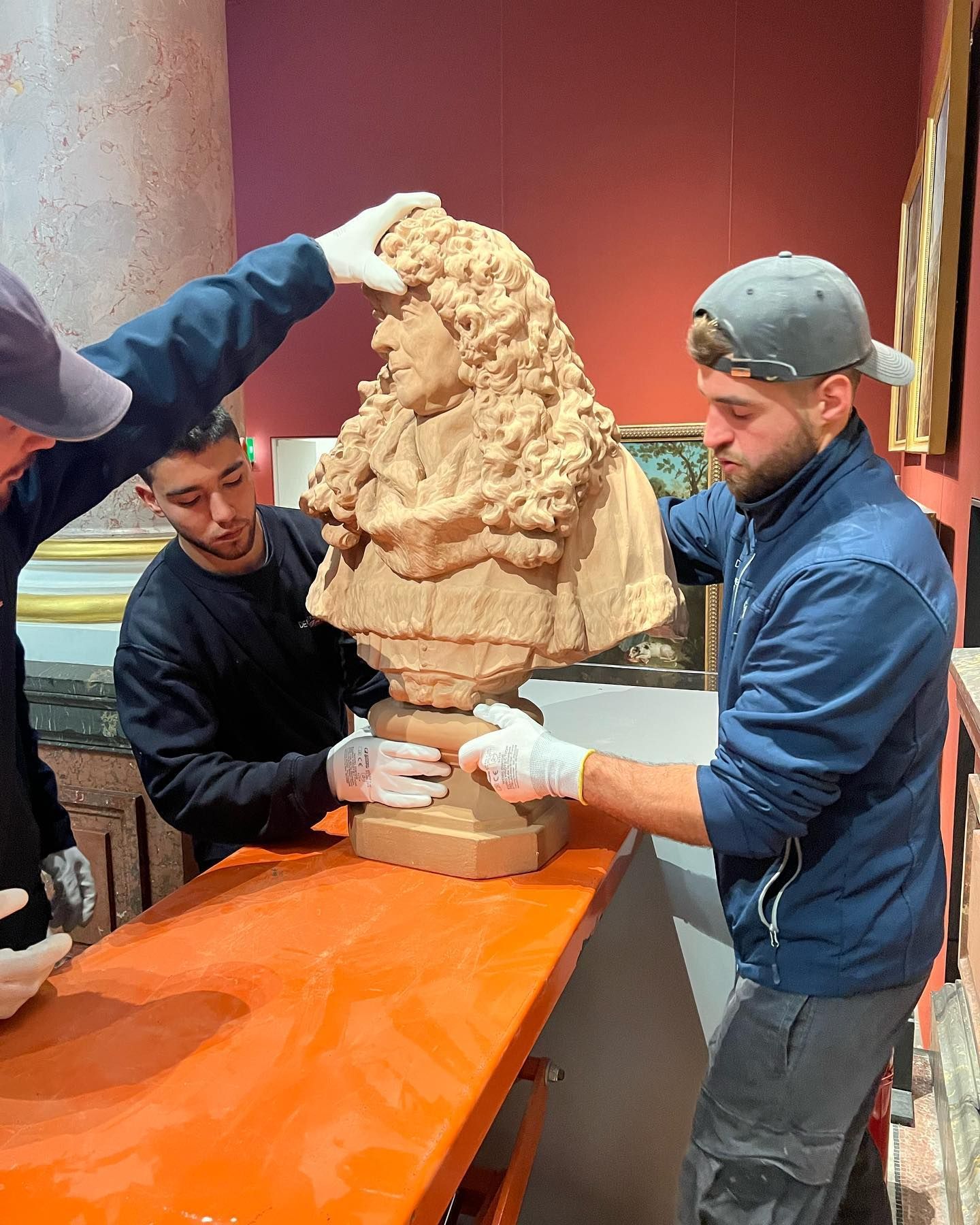 Équipe de déménageurs qui s'apprêtent à emballer un buste dans un musée