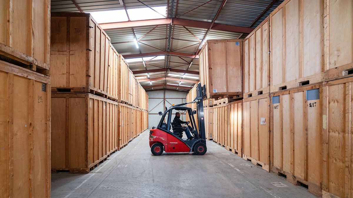 Homme dans un chariot élévateur rouge qui prend un box de garde-meubles