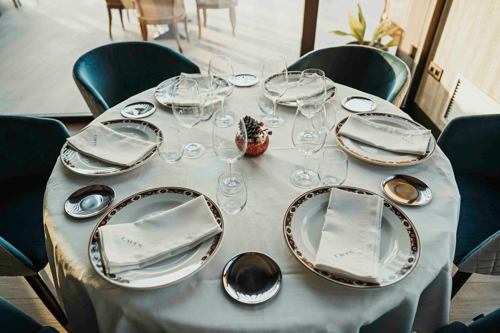 Una mesa redonda con platos, servilletas, vasos y cubiertos sobre ella en un restaurante.
