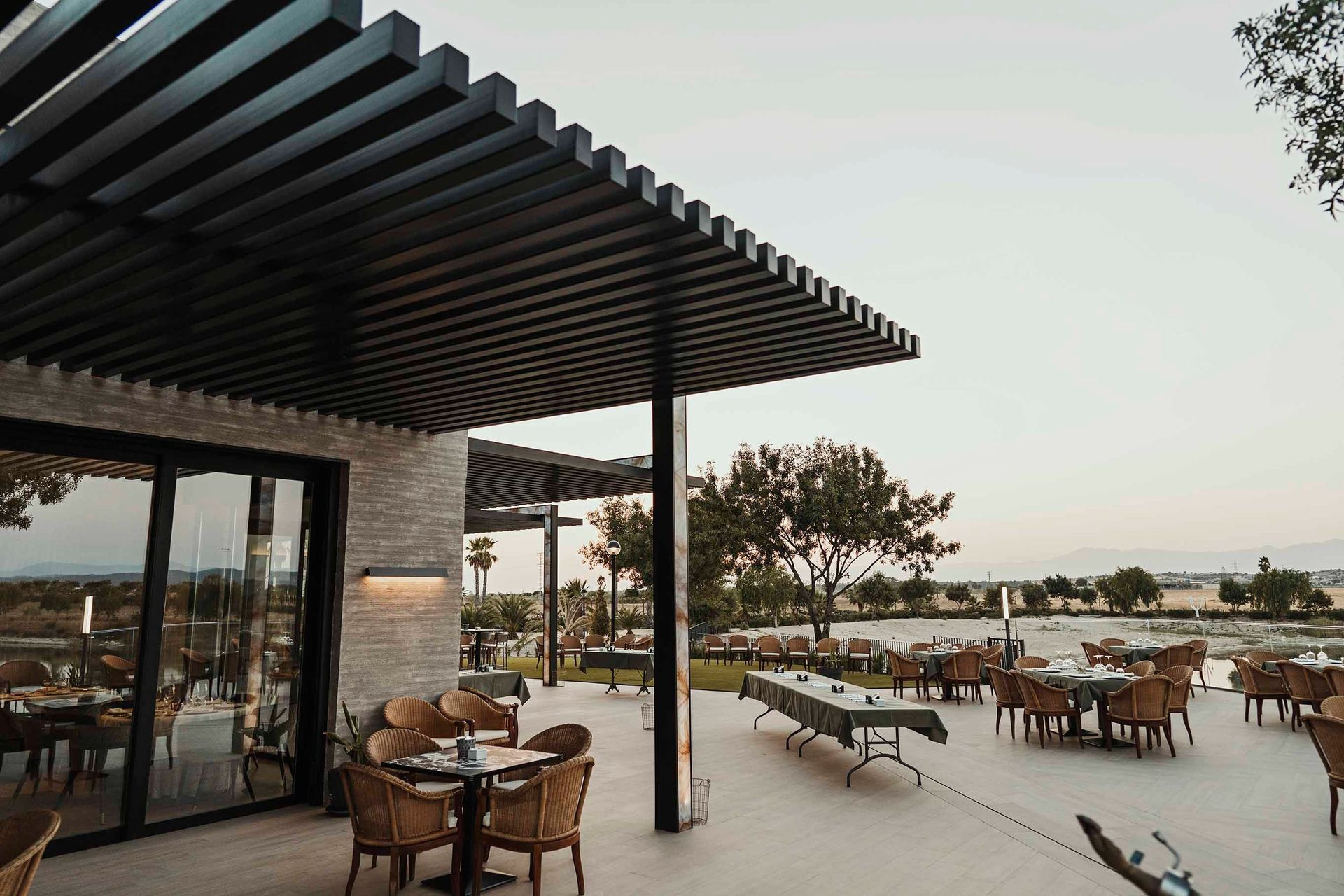 Un restaurante con mesas y sillas bajo una pérgola.