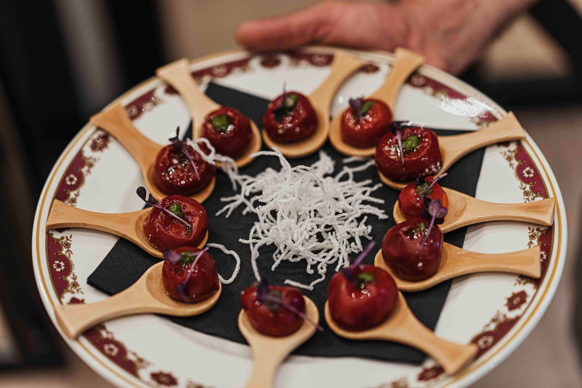 Una persona sostiene un plato de comida con cucharas de madera sobre él.