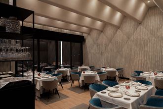 Un gran comedor con mesas y sillas preparadas para la cena.
