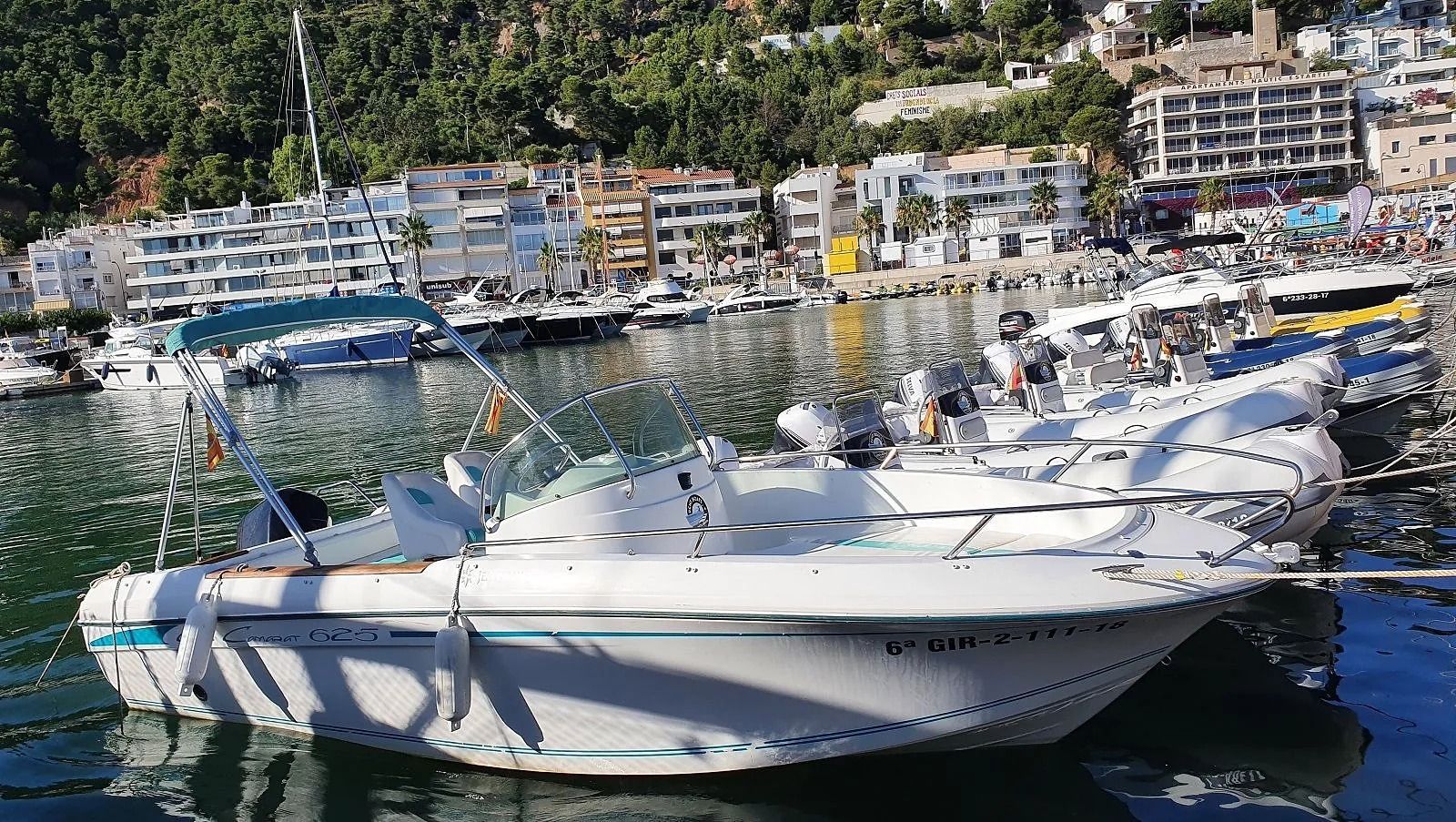 Un barco blanco está atracado en un puerto con una ciudad al fondo.