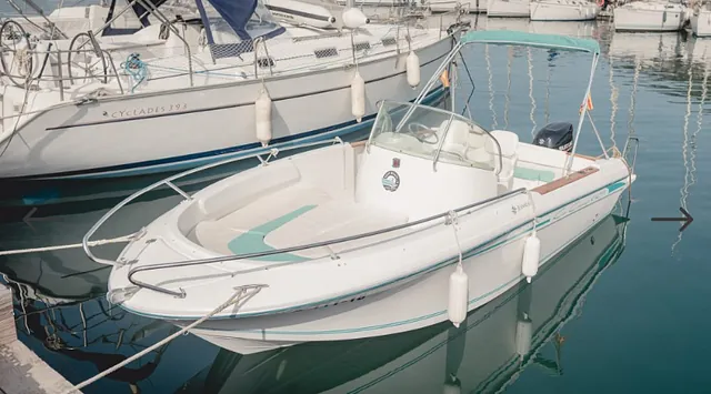 Un barco blanco está atracado en un puerto junto a otros barcos.