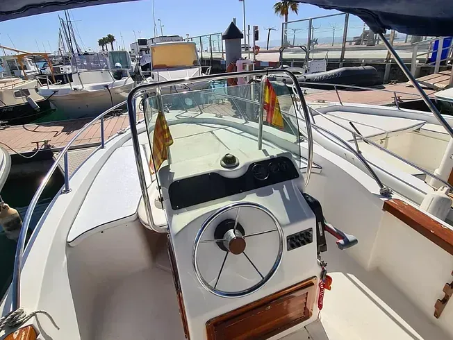 Un barco con volante está atracado en un puerto deportivo.