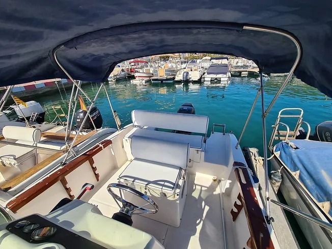 Un barco con un toldo azul está atracado en un puerto deportivo.