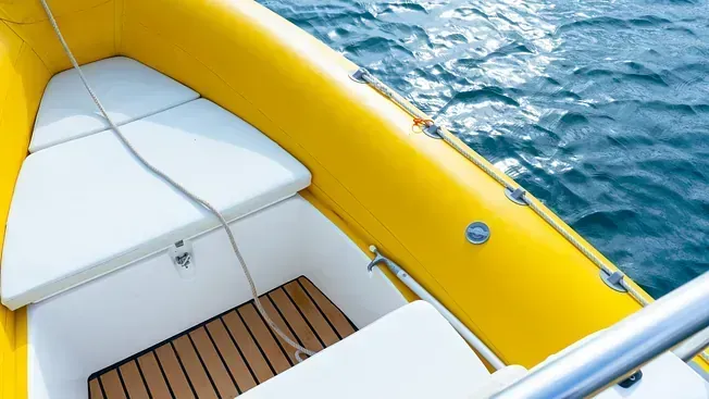 Un barco amarillo y blanco flota sobre un cuerpo de agua.