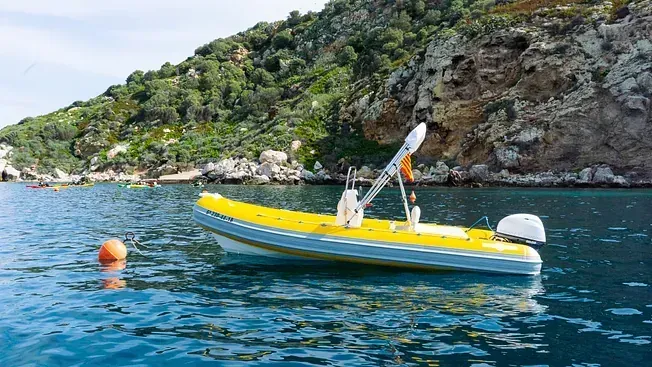 Un barco amarillo y blanco flota sobre un cuerpo de agua.
