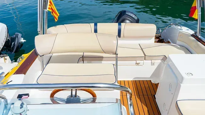 La parte trasera de un barco con un volante y un sofá en el agua.