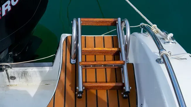 Un barco con una escalera de madera sujeta a un costado.