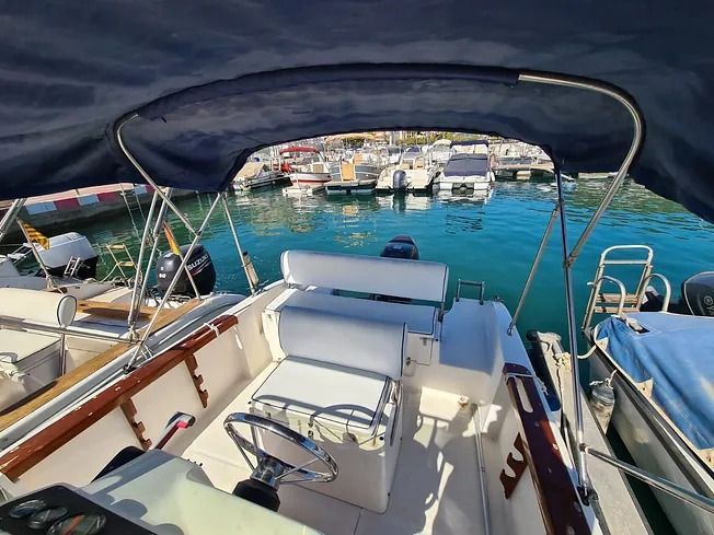 Un barco con un toldo azul está atracado en un puerto deportivo.