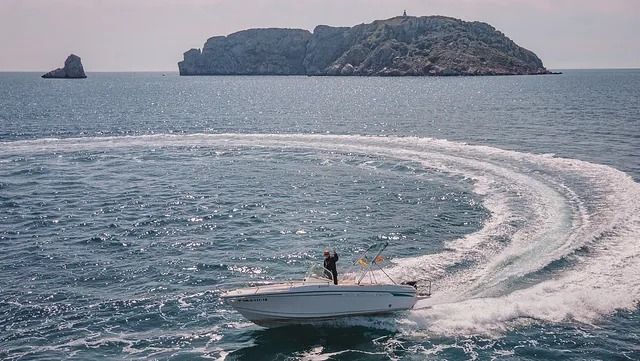 Un barco flota sobre un cuerpo de agua con una pequeña isla al fondo.
