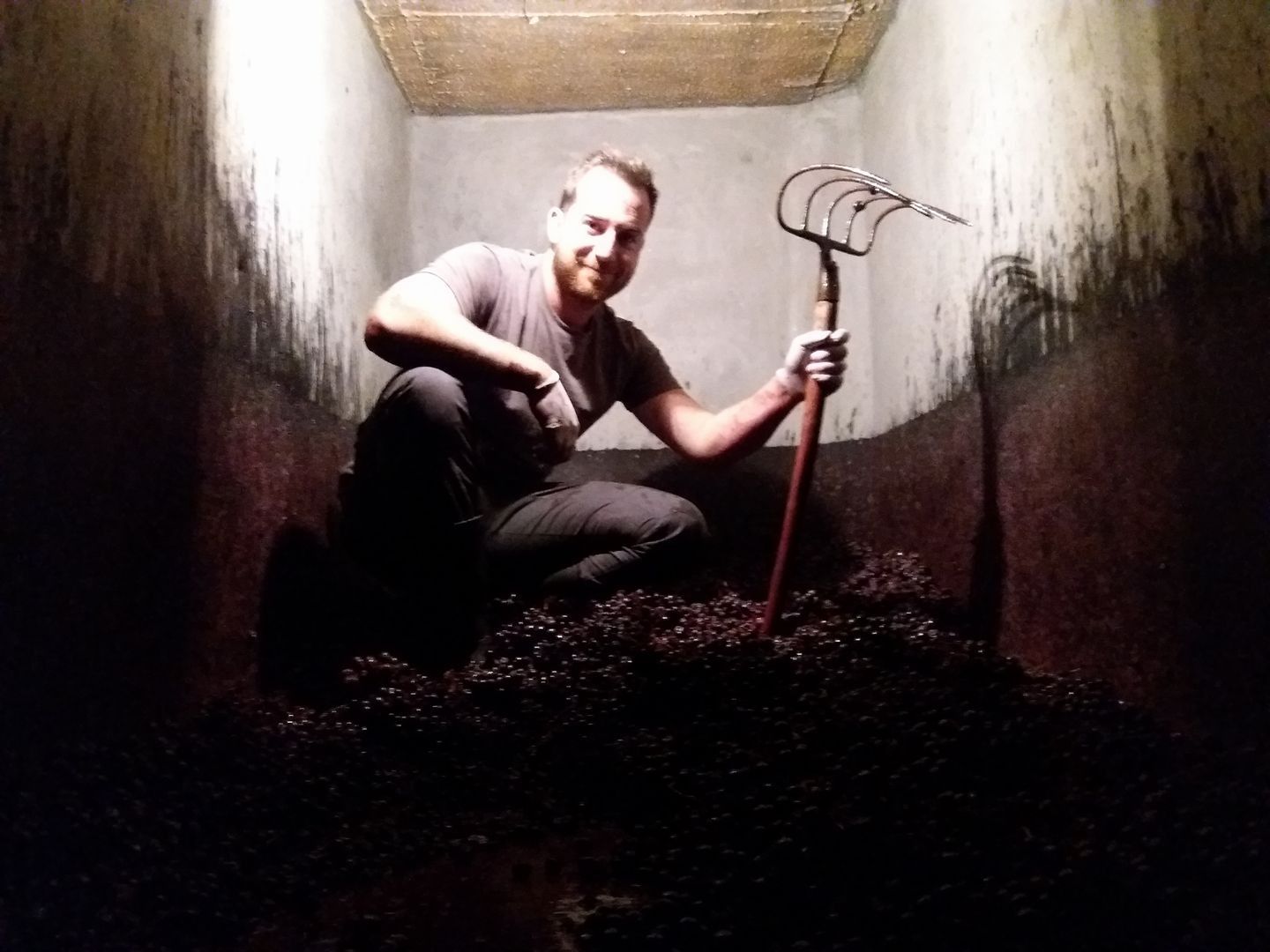 Un hombre está arrodillado en una habitación oscura sosteniendo un rastrillo.