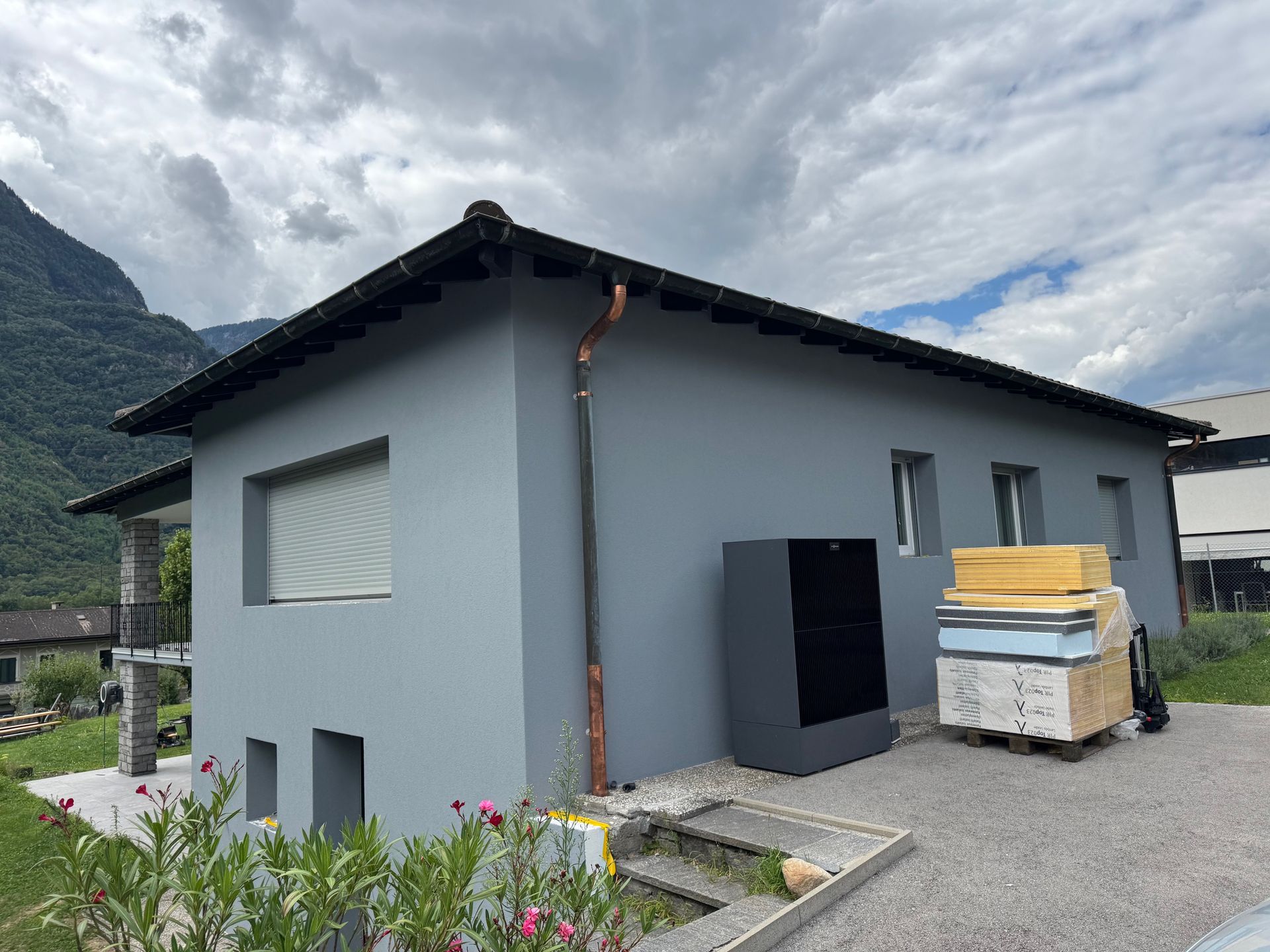 Edificio di servizio giallo con porta e tetto blu, accanto a un'area erbosa.