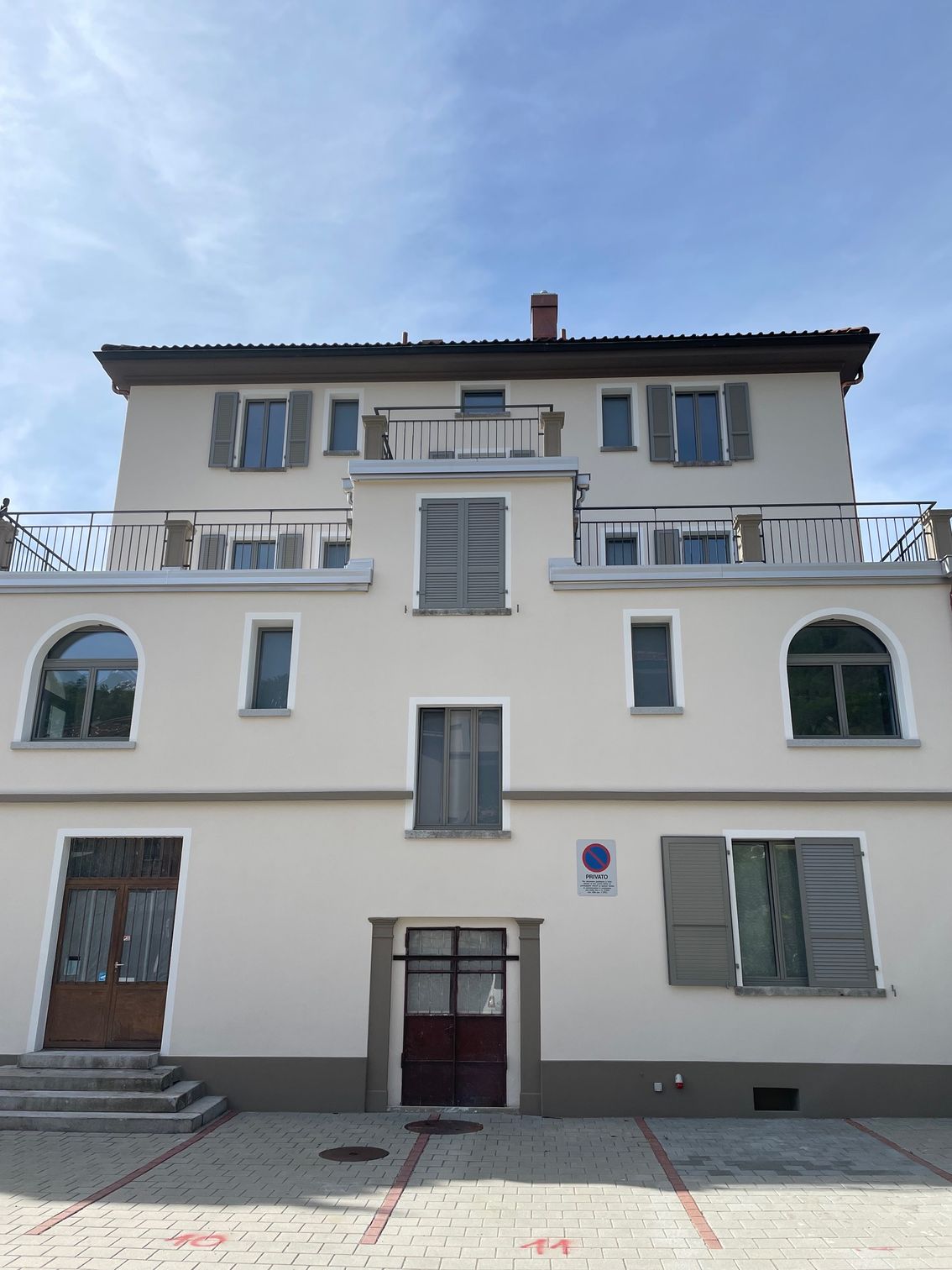 Due operai su un'impalcatura stanno dipingendo una casa bianca a due piani con un balcone di fronte a una montagna.