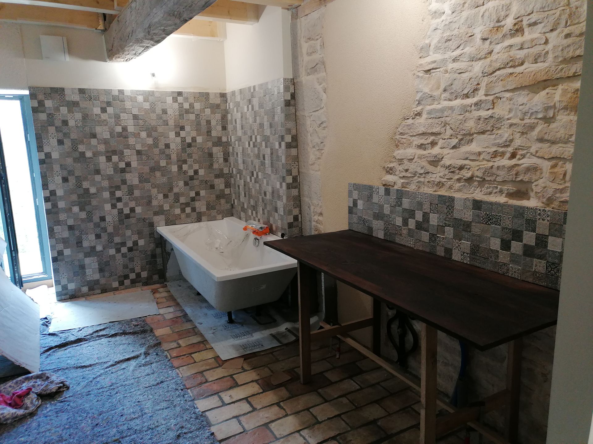 Salle de bains avec murs carrelés, douche, meuble-lavabo et miroir. Porte-serviettes blanc à gauche.