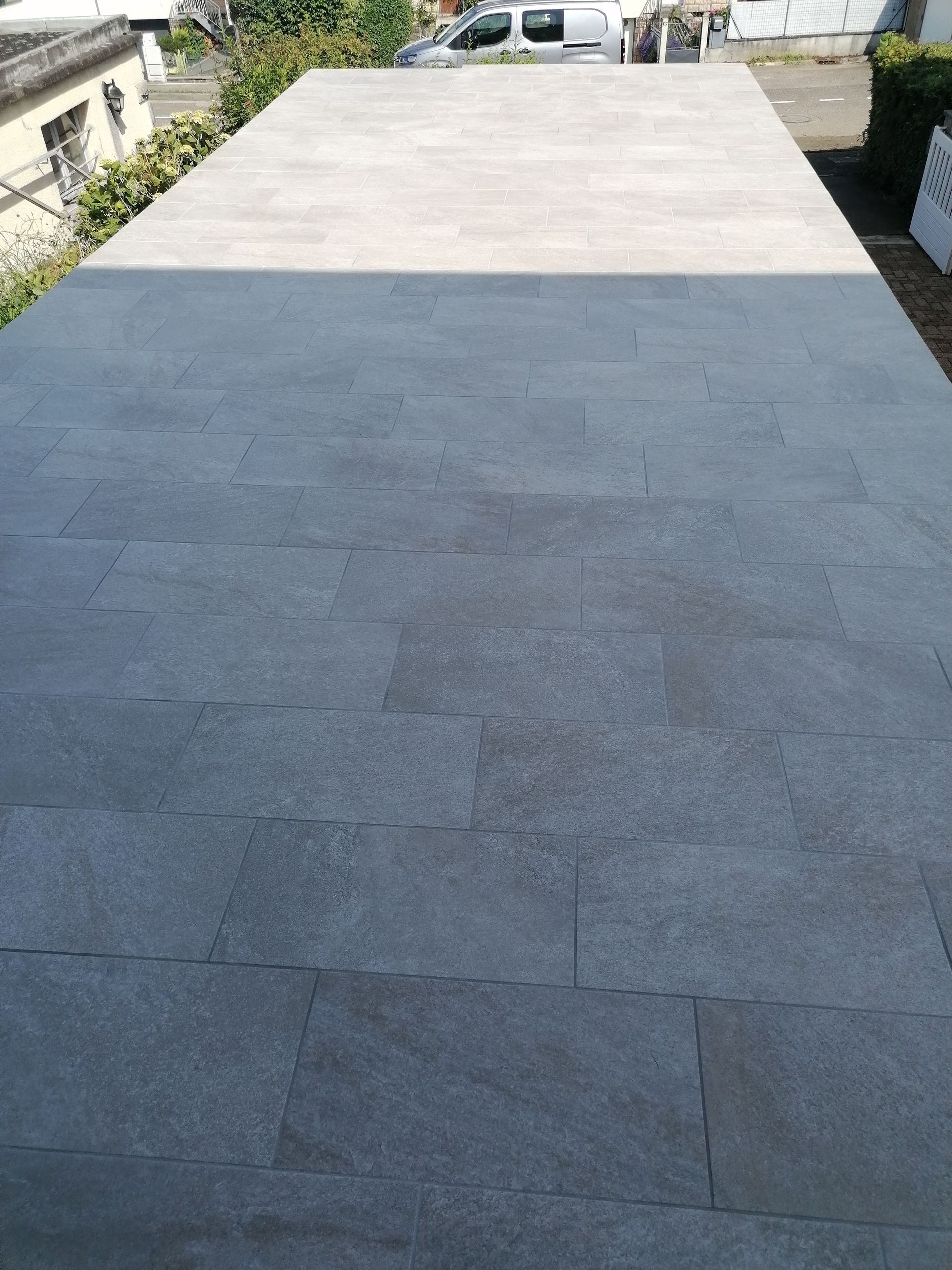 Une surface plane et pavée, recouverte de pierres grises carrées, passant d'une teinte plus foncée au premier plan à un gris clair.