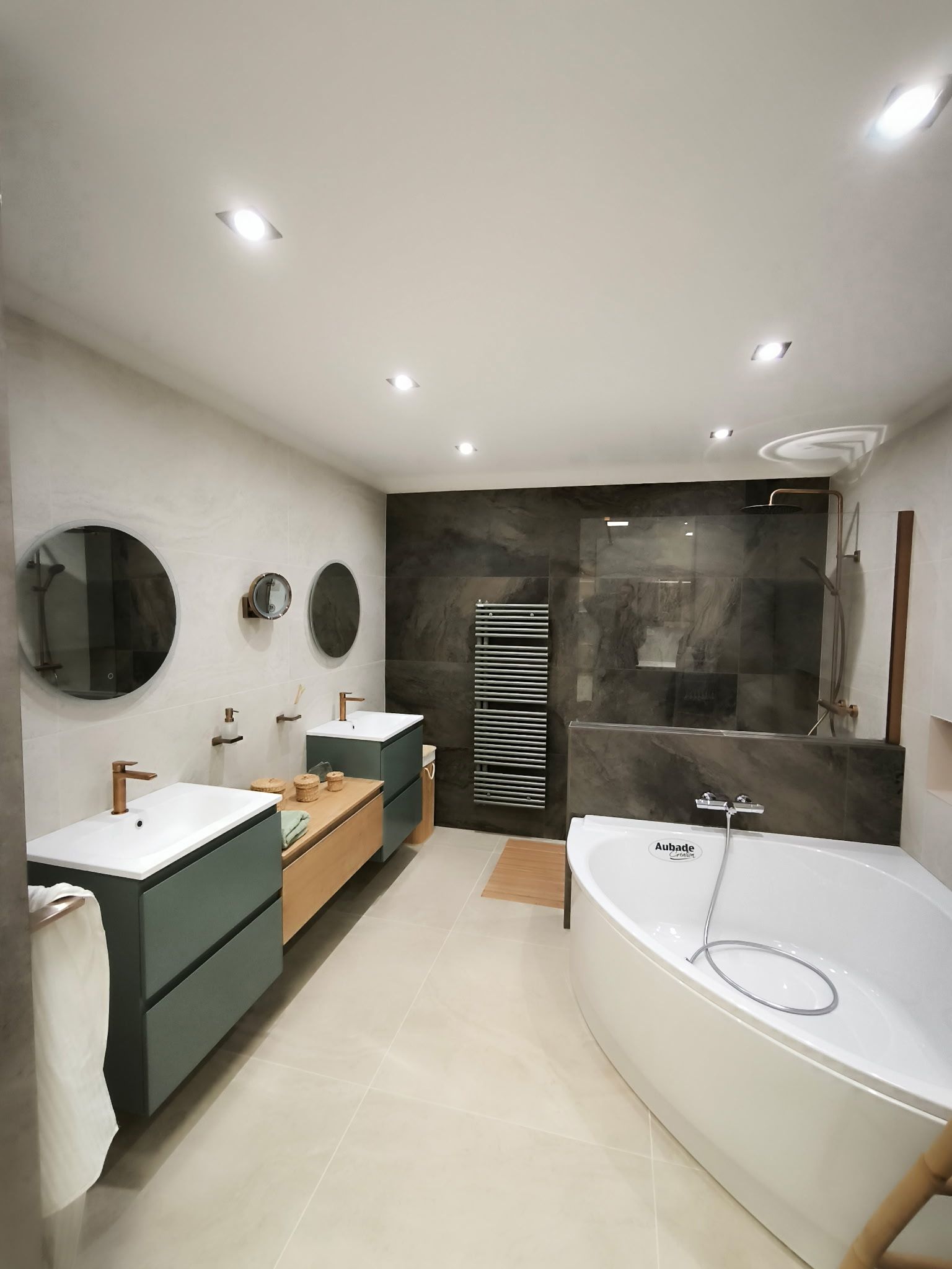 Cabine de douche avec murs et sol carrelés beiges, paroi en verre, pommeau de douche chromé, en construction.