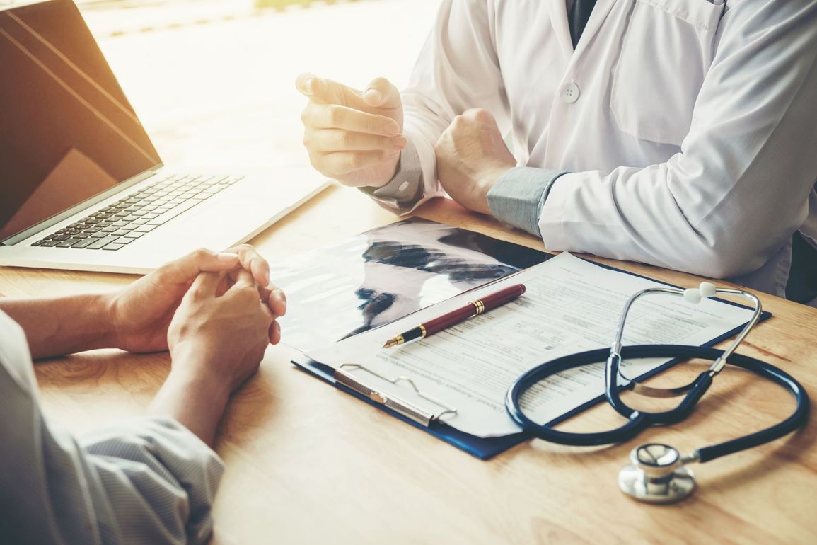 Photo d'un médecin et d'un patient assis à un bureau avec une radio sur la table