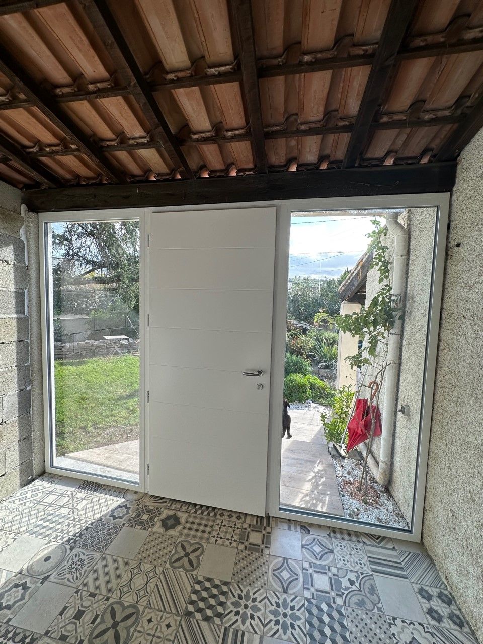 Porte blanche entre deux grandes vitres menant vers l'extérieur