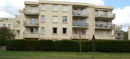 Immeubles d'appartements à plusieurs étages avec balcons derrière une haie.