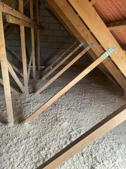 Grenier avec poutres apparentes et isolation, sous une toiture en tuiles rouges.