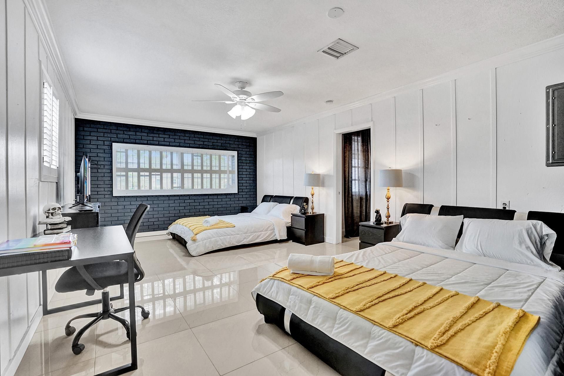 A bedroom with two beds , a desk and a ceiling fan.