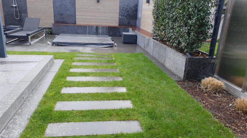 Ein üppiger grüner Rasen mit einem Gehweg, der zu einer Dusche führt.