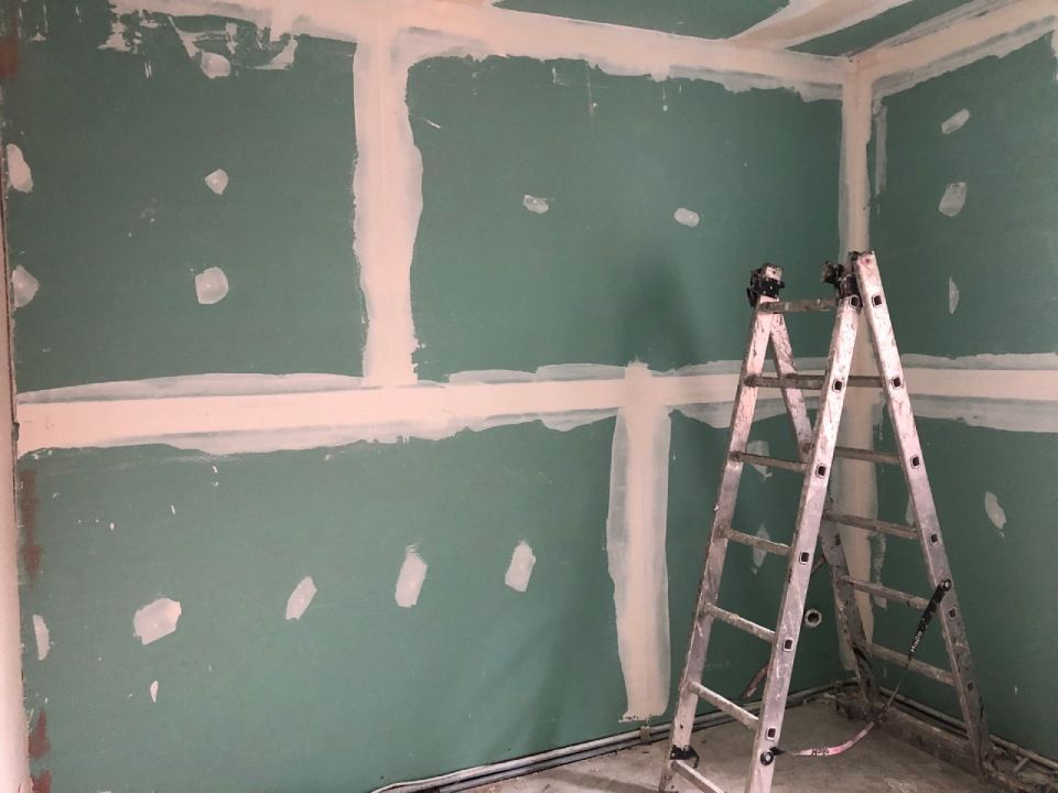 In einem Raum im Bau lehnt eine Leiter an einer Wand.