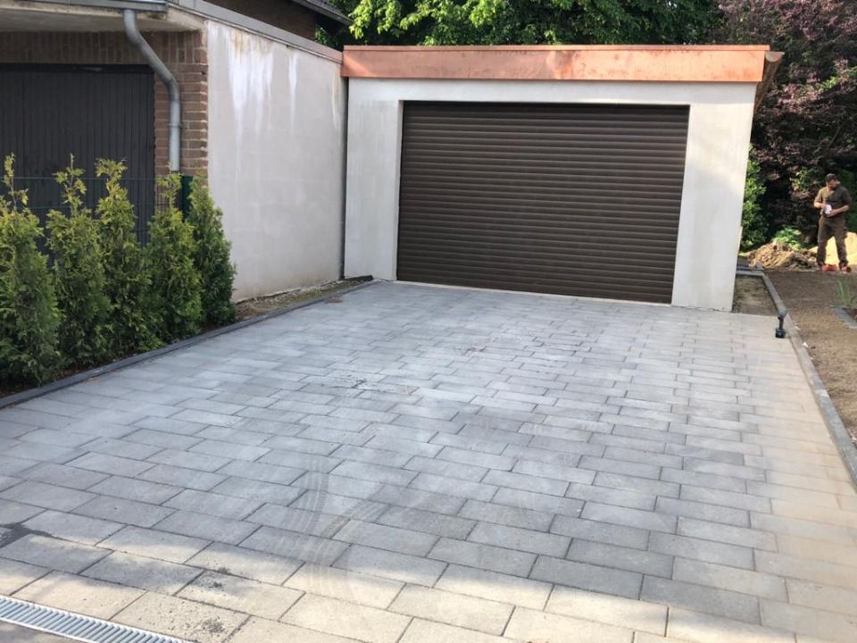 Eine gepflasterte Auffahrt, die zu einer Garage mit Garagentor führt.