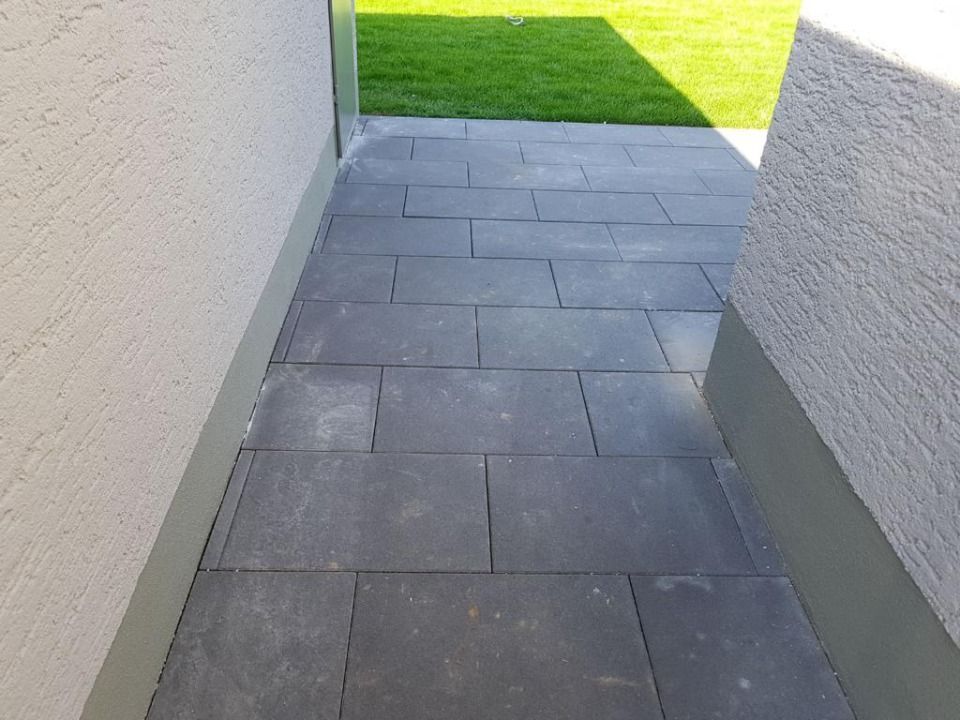 Ein Gehweg zwischen zwei Gebäuden mit einem Rasen im Hintergrund.