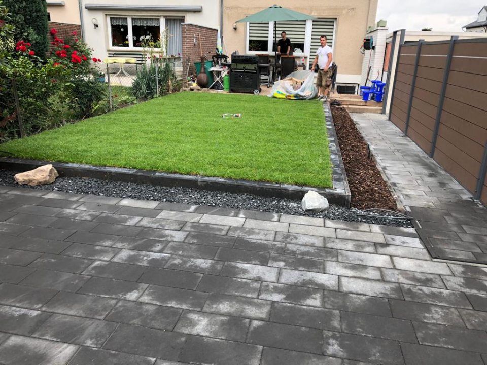 Ein Mann steht vor einem üppigen grünen Rasen.