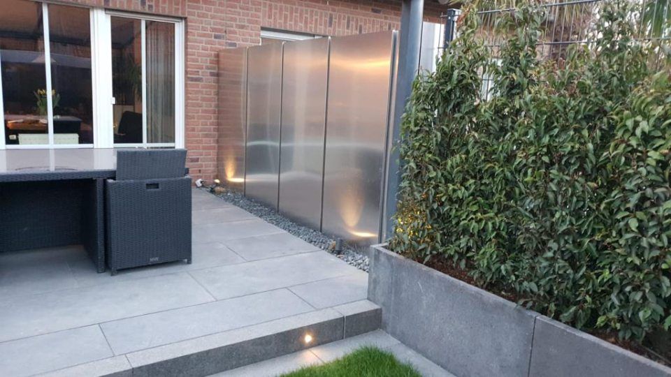 Eine Terrasse mit Tisch und Stühlen und einem Edelstahlzaun.