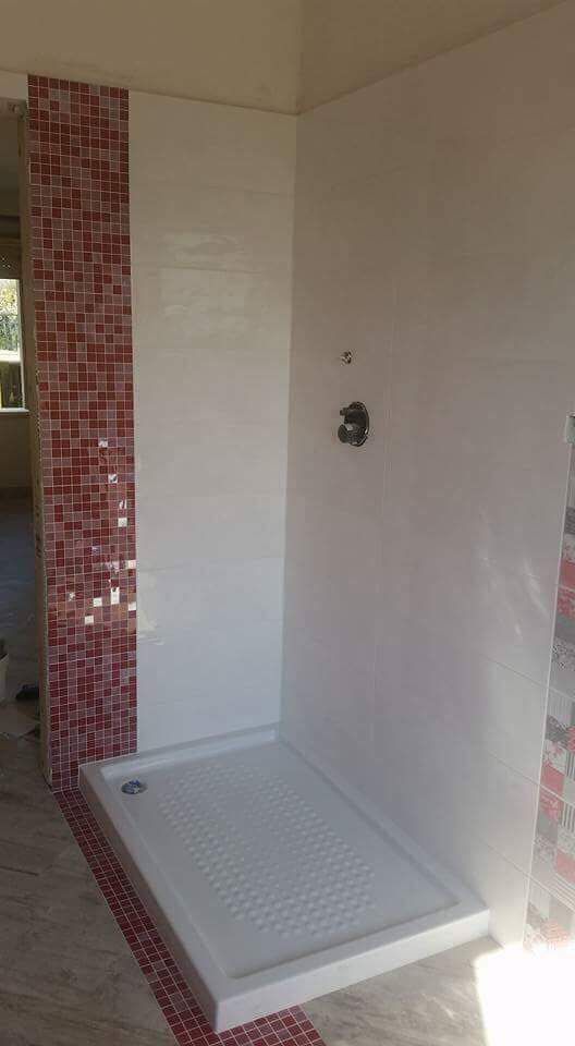 Eine Duschkabine in einem Badezimmer mit roten und weißen Fliesen.