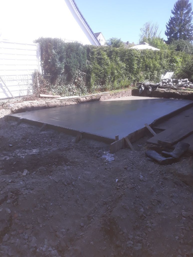 Eine große Betonplatte liegt im Dreck vor einem Haus.