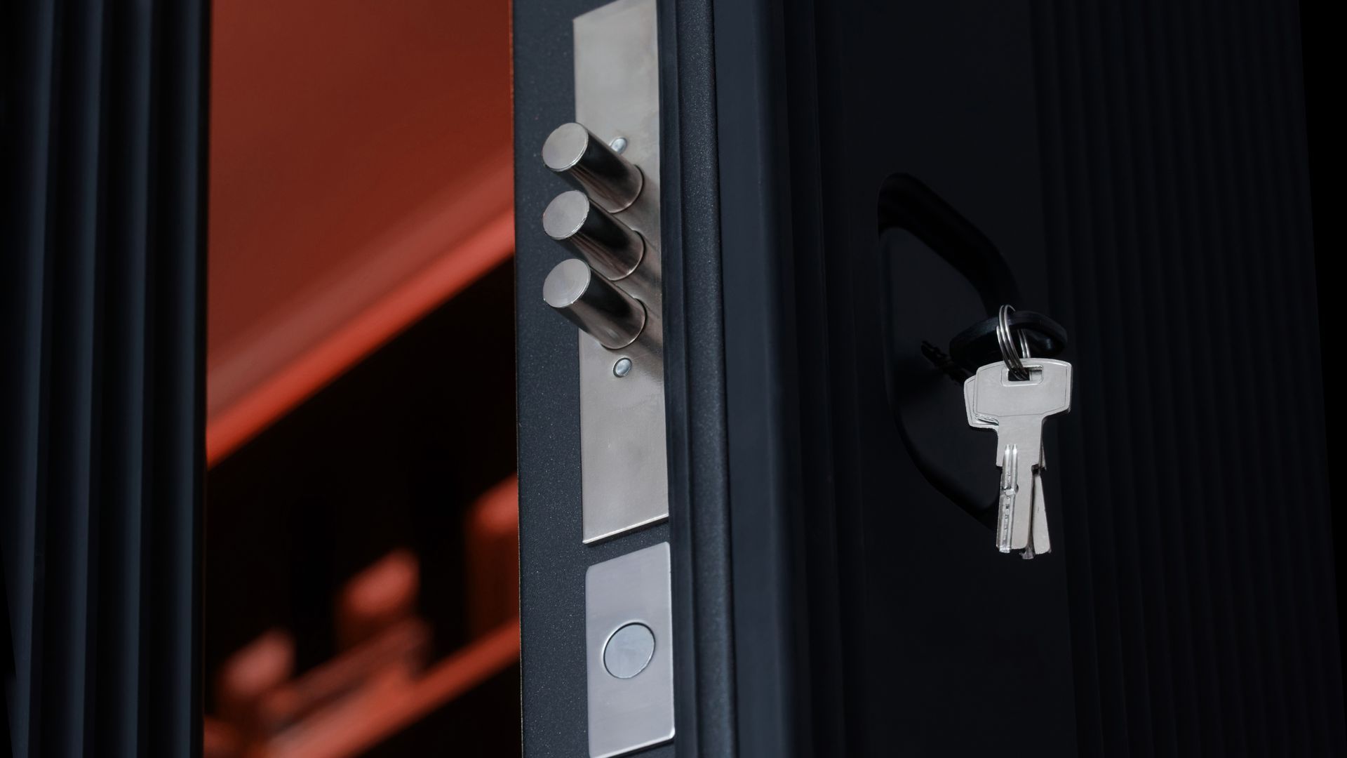 Serrure de porte avec clés accrochées à côté d'un cadre de porte sombre, avec une lumière orange chaude en arrière-plan