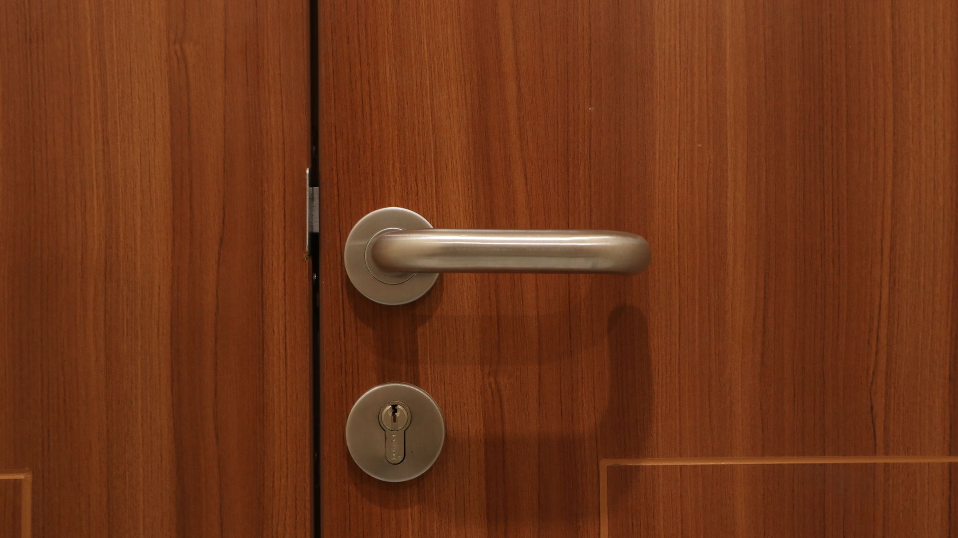 Porte en bois fermée avec poignée argentée et serrure à clé.