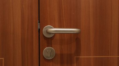 Gros plan sur une poignée de porte argentée et une serrure sur une porte en bois.