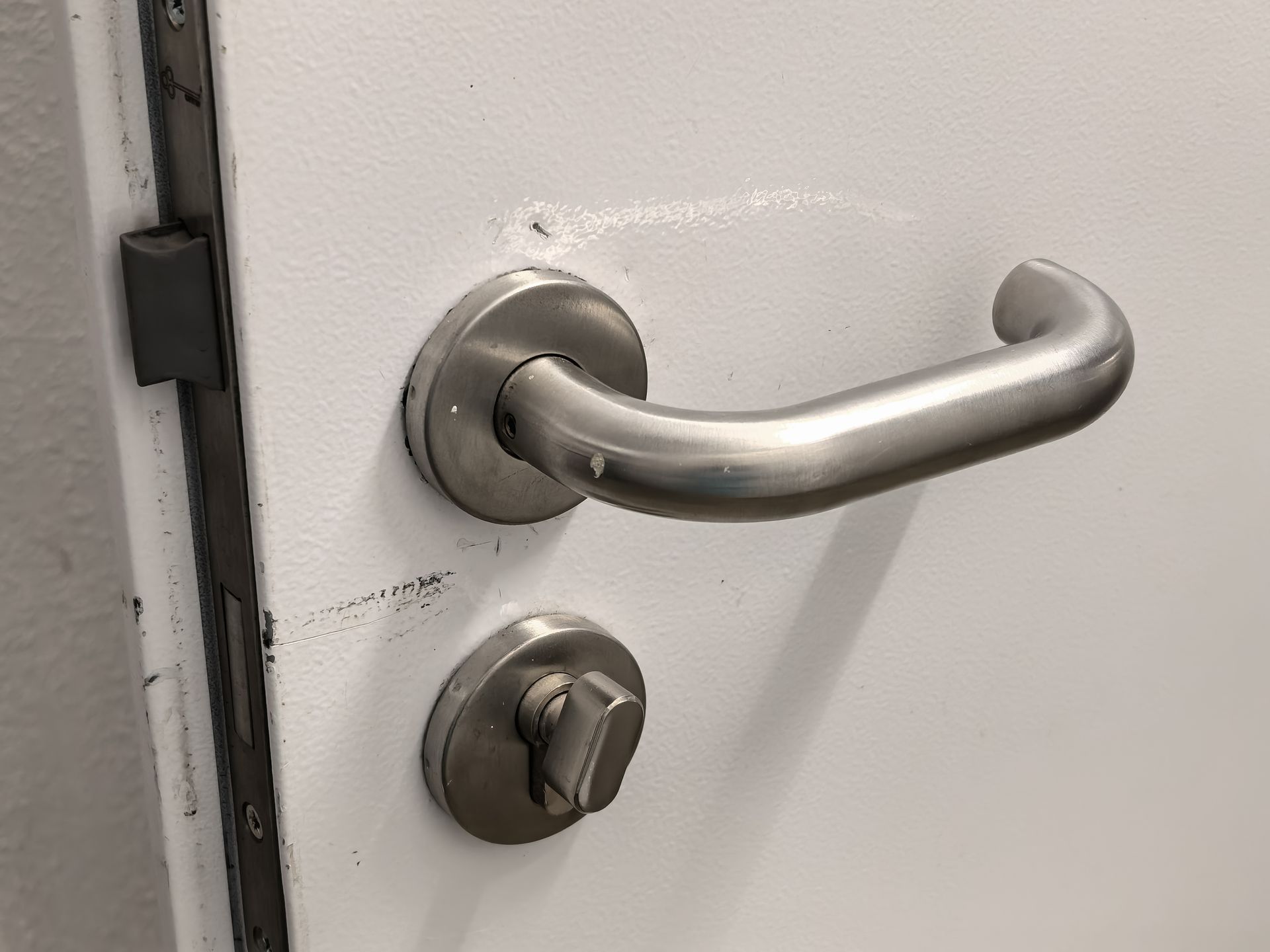 Poignée et serrure de porte en acier inoxydable sur une porte blanche.