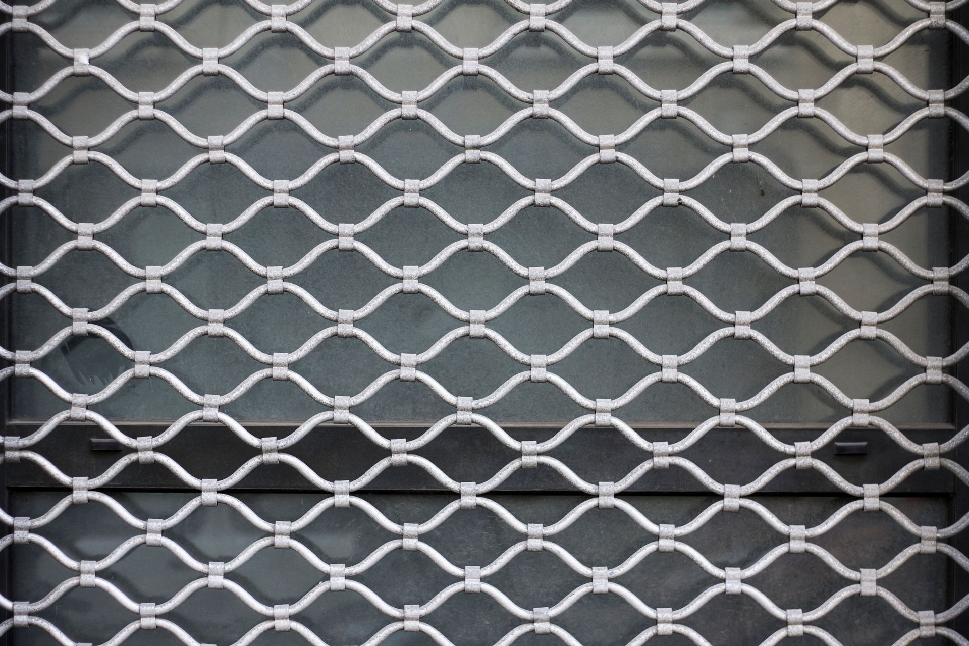 Portail de sécurité fermé en métal blanc avec un motif losange répétitif