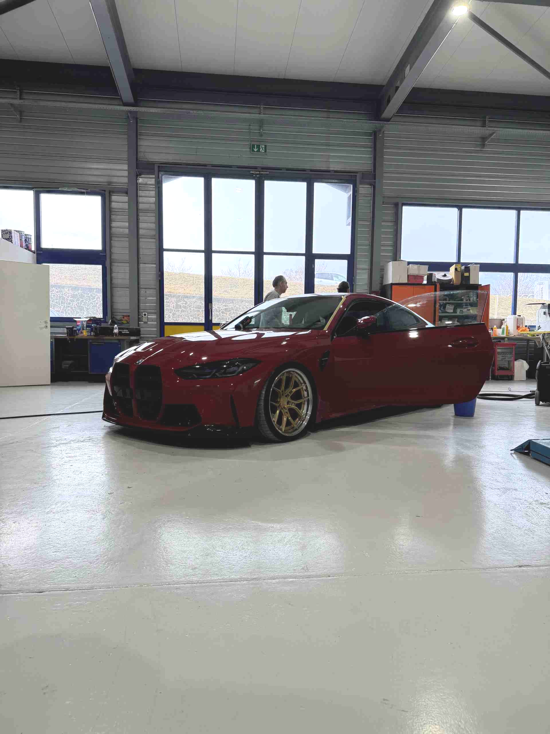 Une BMW sport rouge foncé, basse et racée, avec des jantes dorées