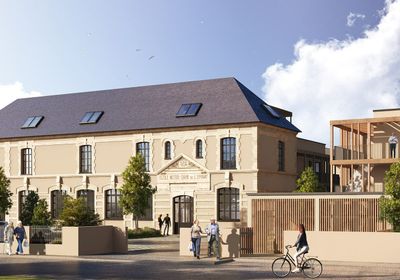 Bâtiment beige au toit sombre, jouxtant une structure moderne en bois.