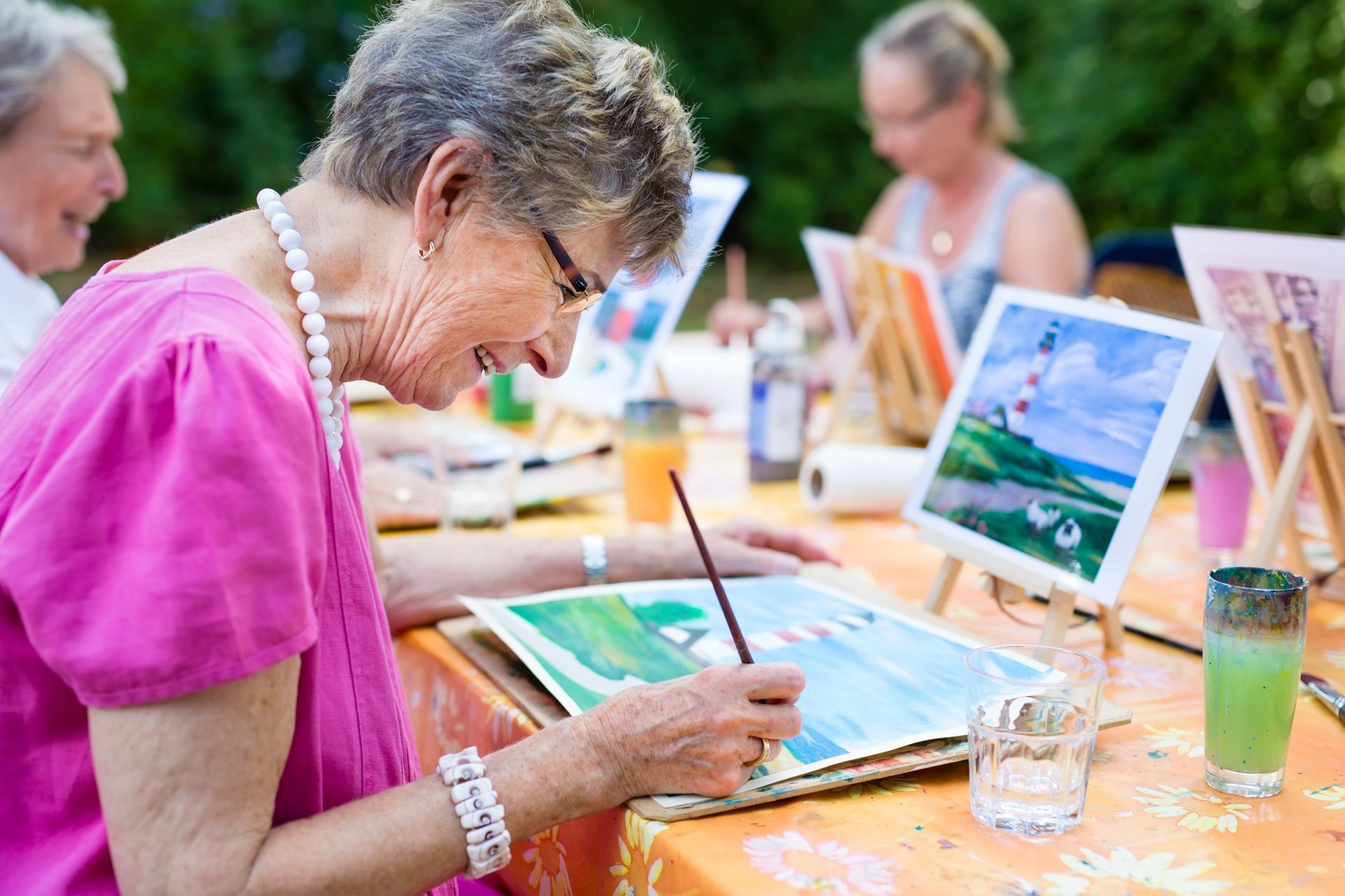 Une femme peint en plein air, assise à une table.