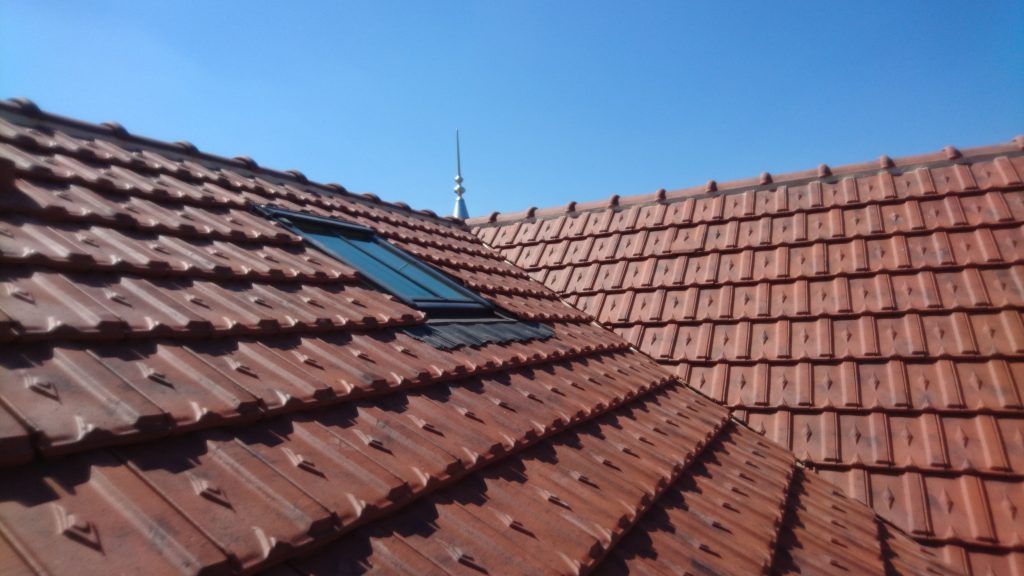 Toits de tuiles rouges avec une lucarne sous un ciel bleu clair