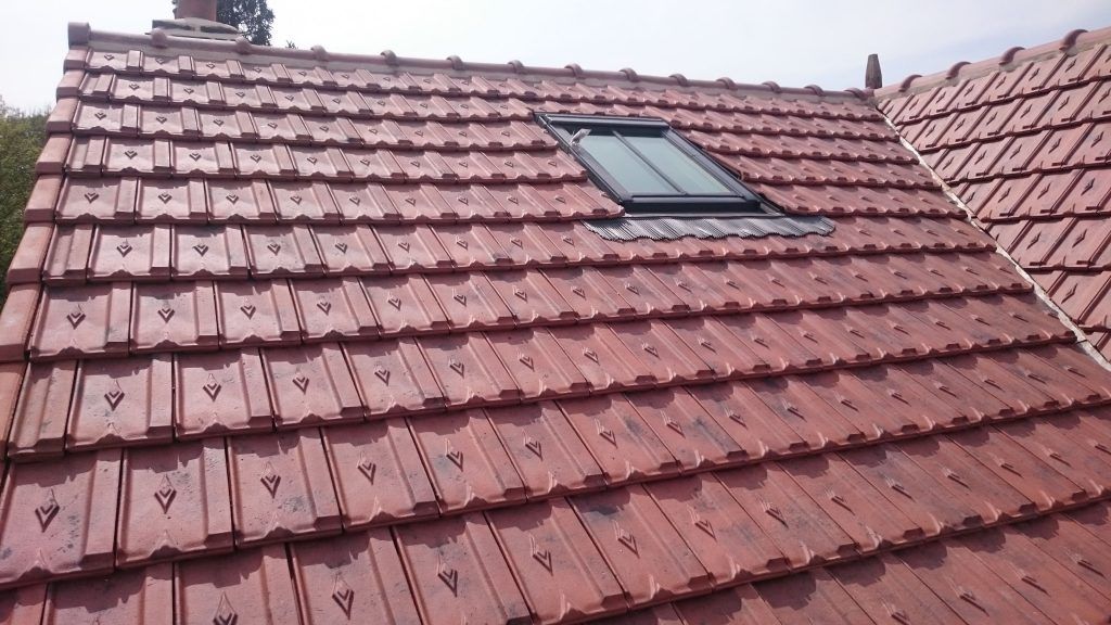 Maison avec un toit de tuiles rouges et une fenêtre de toit.
