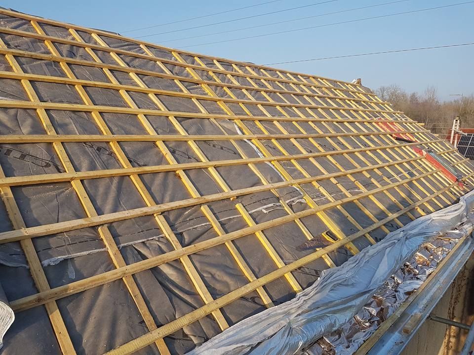 Toiture en construction avec charpente en treillis de bois sur sous-couche noire, sur une surface inclinée