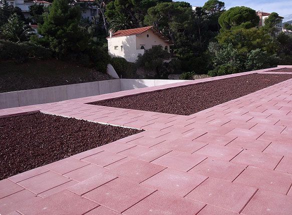 Terrasse sur le toit carrelée de rose avec jardinières en gravier et arbres en arrière-plan