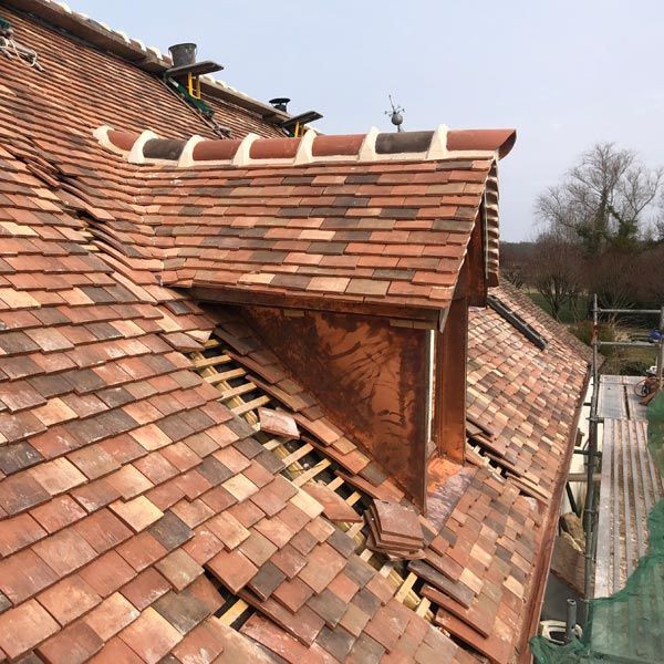 Toiture en tuiles de terre cuite rouge et lucarne en construction sur le toit d'une maison.