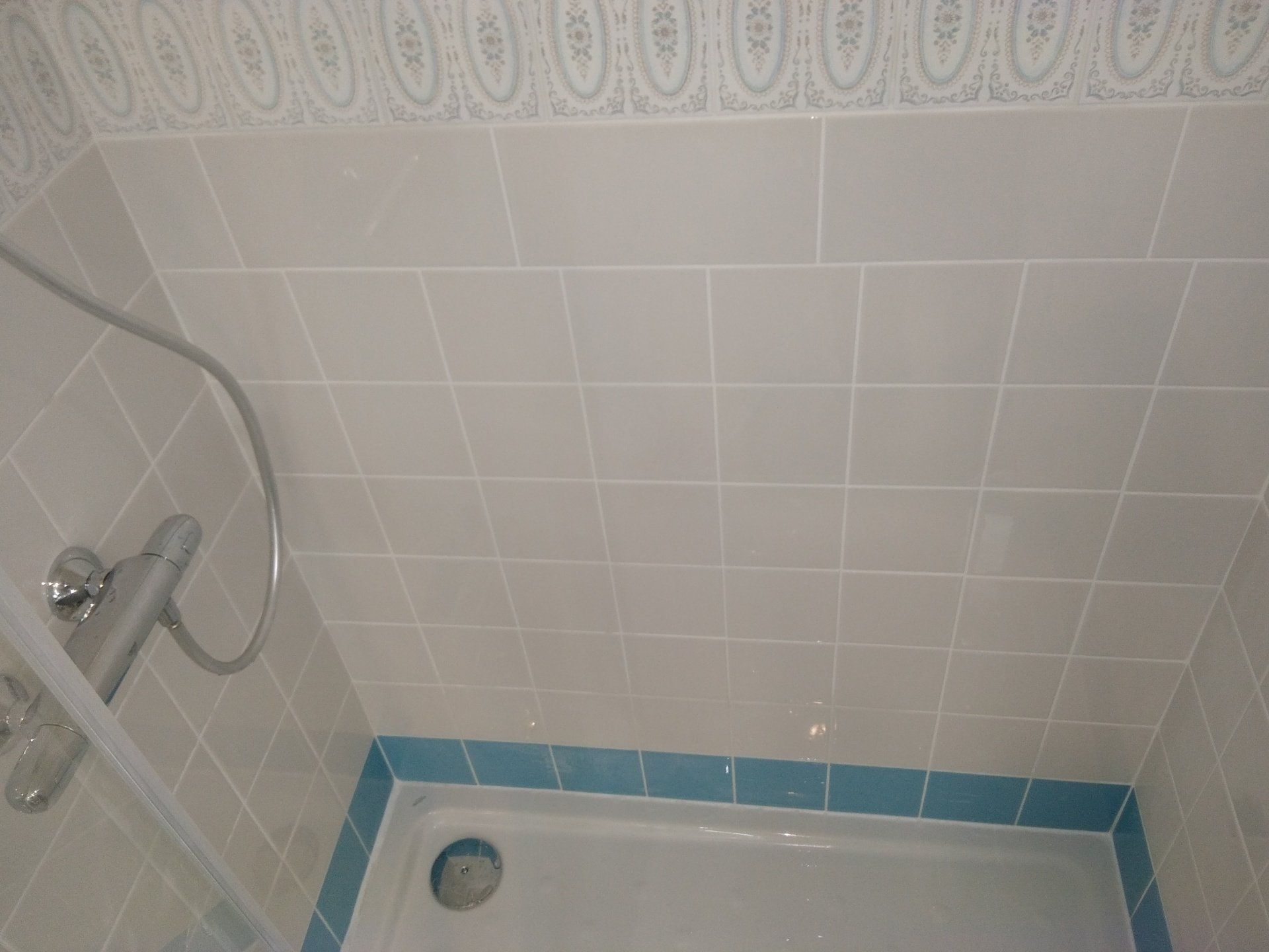 Cabine de douche avec du carrelage bleu et blanc